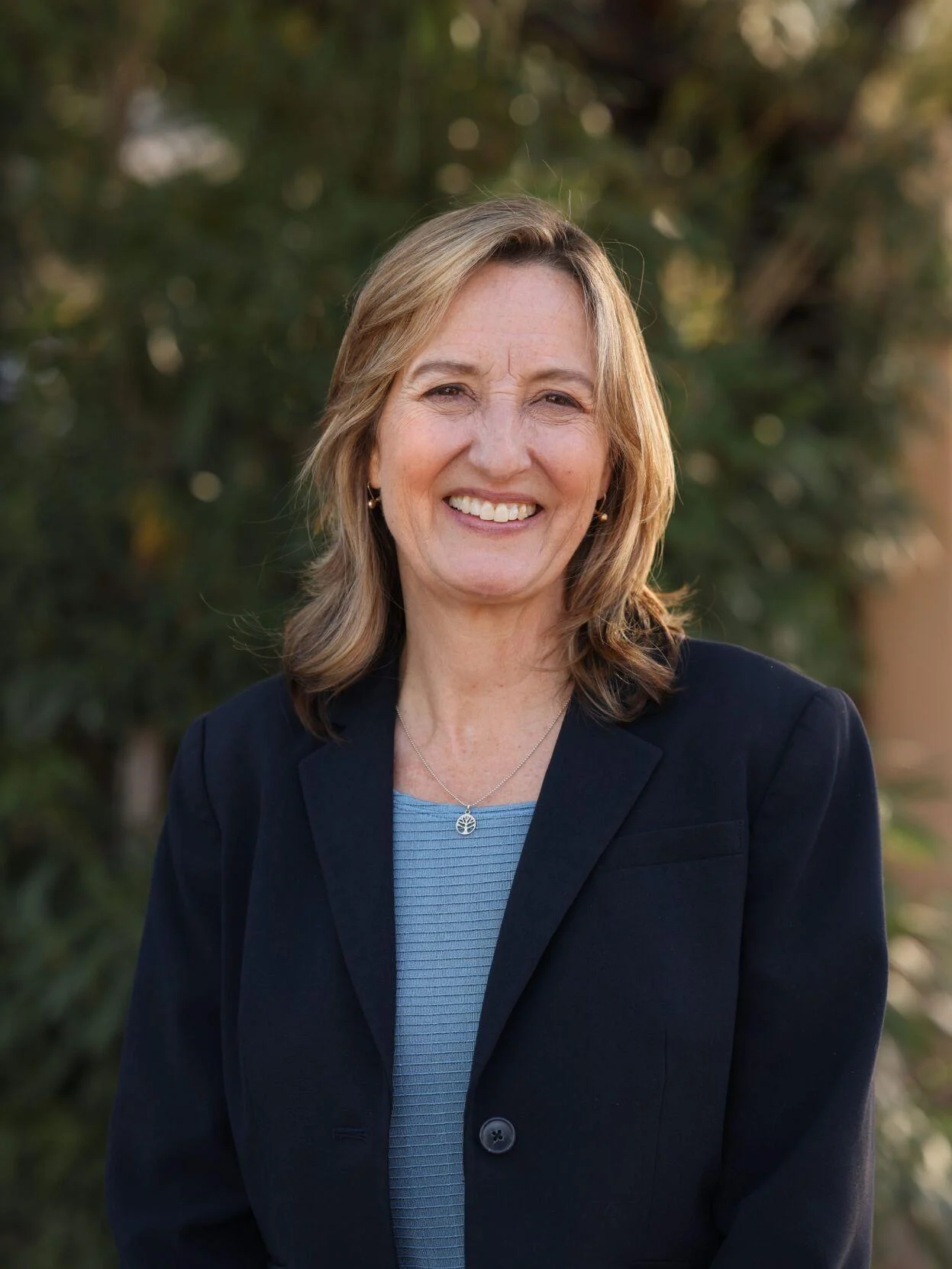 Candidate for Congress Kirsten Engel wearing a navy blue blazer, with a light blue top under. She is smiling, gazing at the camera.