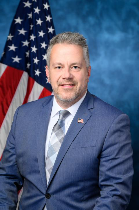 Headshot of Eric Sorrenson in a blue blazer, white shirt and blue patterned tie.