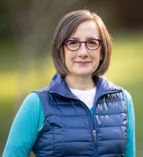 Headshot of Andrea Salina in a blue long sleeve shirt, and a dark blue puffer vest.