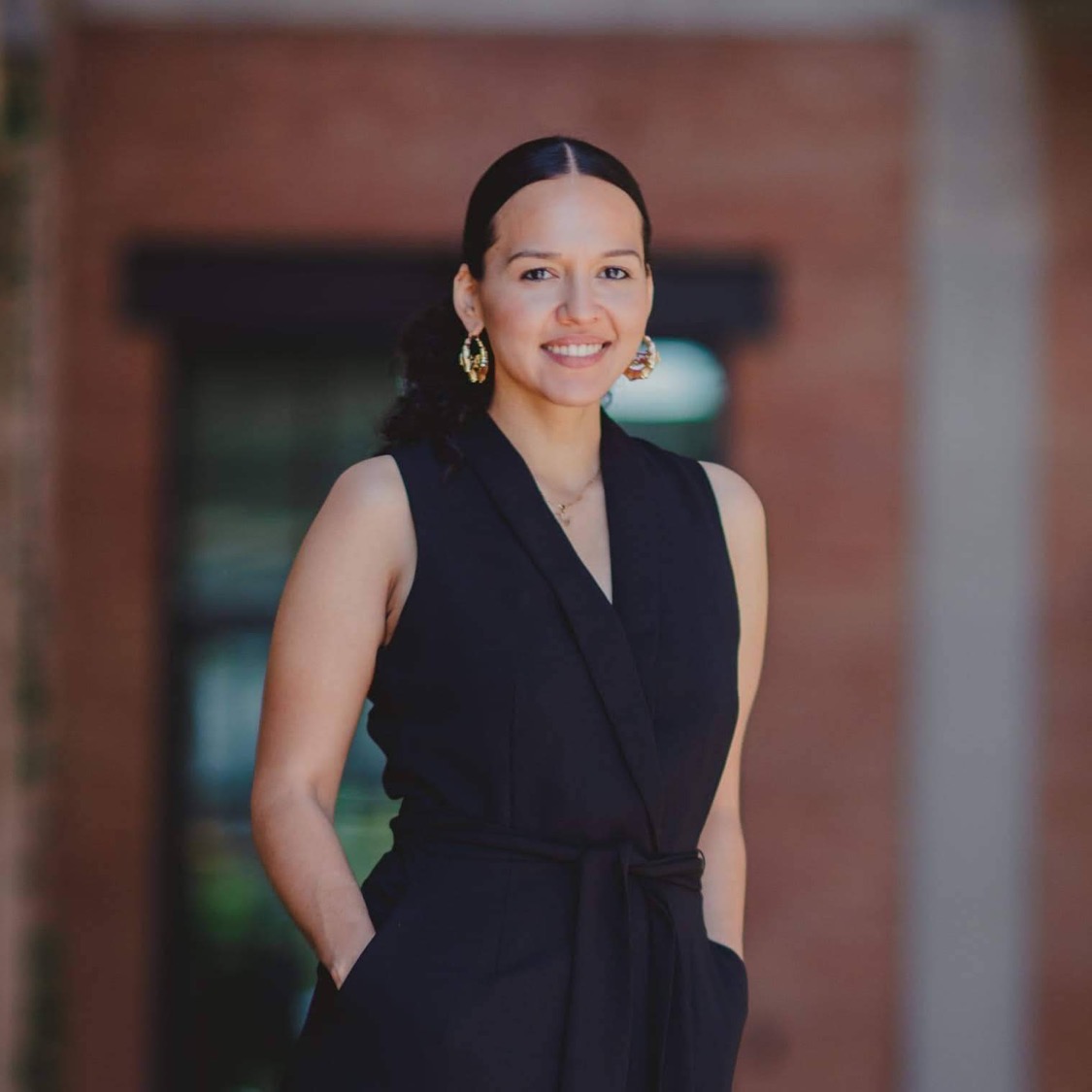 Michelle Vallejo in black outfit with a slicked-back bun.