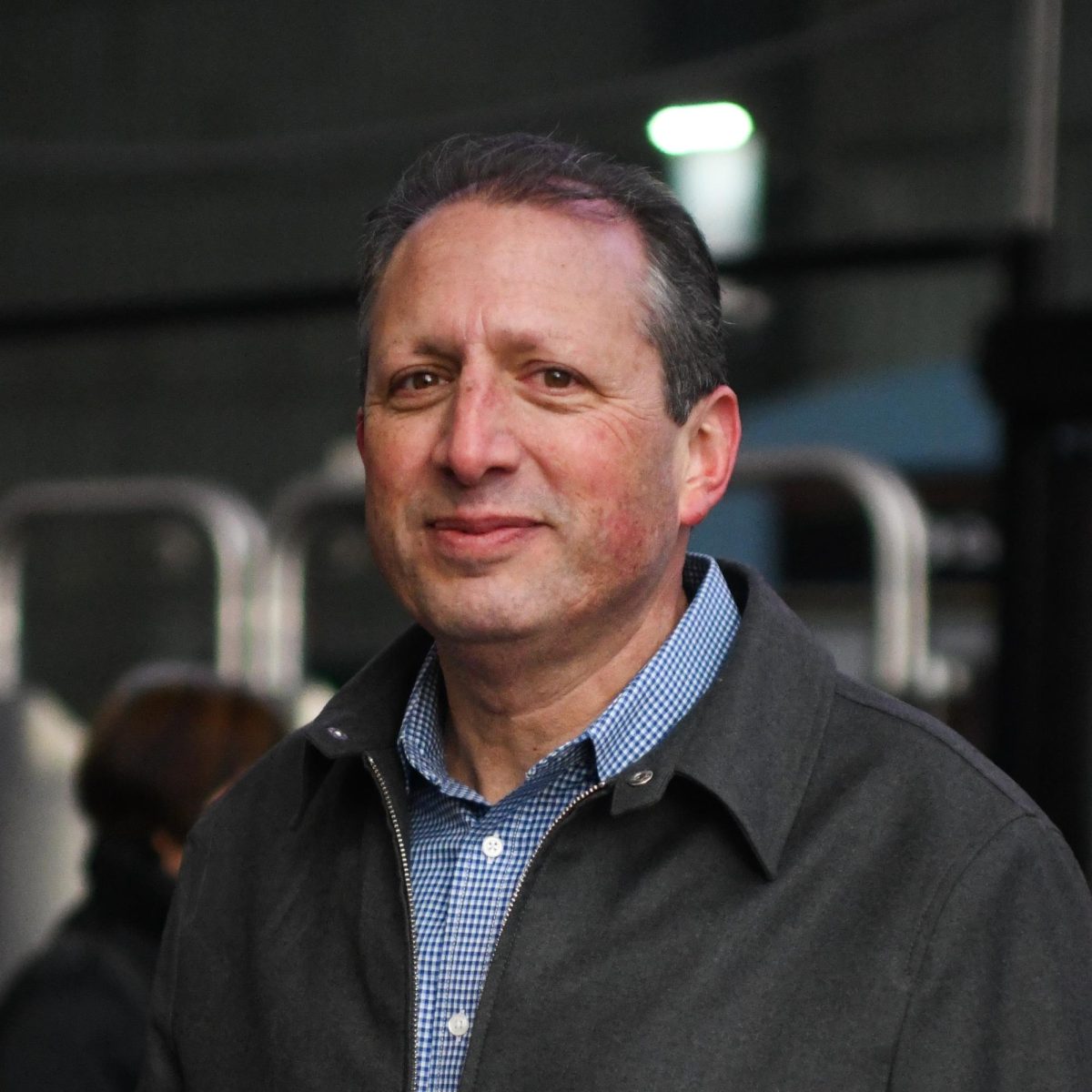 Brad Lander portrait. He's smiling at the camera wearing a grey jacket and blue collared shirt.